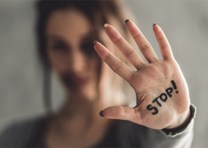 Woman holding up hand with the word Stop written on her hand