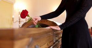Woman placing flowers on a casket.