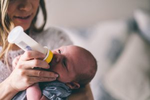 Mother feeding newborn out of a bottle.