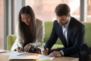 Couple sitting on sofa signing documents