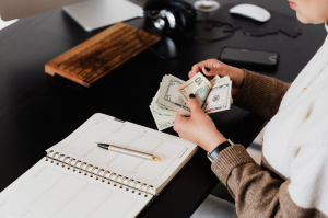 notebook on desk and woman counting money