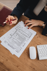 Tax papers on a desk with woman's hands holding a pen