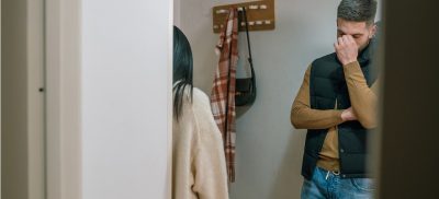 Man with hand on face standing across from a woman