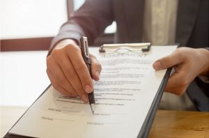 Hands holding a clipboard with agreement to sign