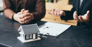 Model of house sitting on desk with clipboard 