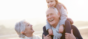 Grandmother and Grandfather smiling with child on his shoulders