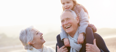 Grandmother and Grandfather smiling with child on his shoulders