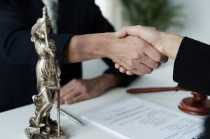 Shaking hands over a desk with papers and a statue