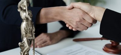 Shaking hands over a desk with papers and a statue