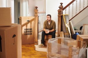 Man sitting in house with boxes packed