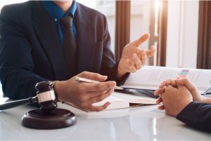 Two people sitting at a desk with books and a gavel