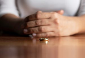 Man's hands folded on a table with a wedding ring