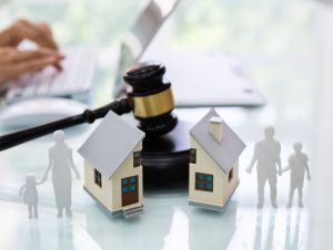 Gavel with house split in half and cutouts of family on either side