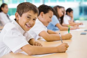 Children sitting at desk with paper and pens