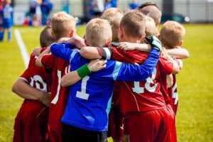 Kids in sports uniforms standing in a huddle