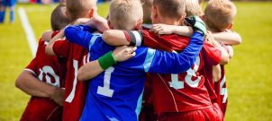 Kids in sports uniforms standing in a huddle
