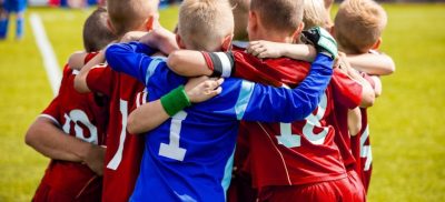 Kids in sports uniforms standing in a huddle