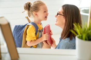 Girl with backpack on smiling at her mother