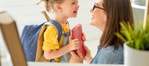Girl with backpack on smiling at her mother