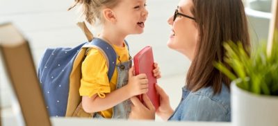 Girl with backpack on smiling at her mother